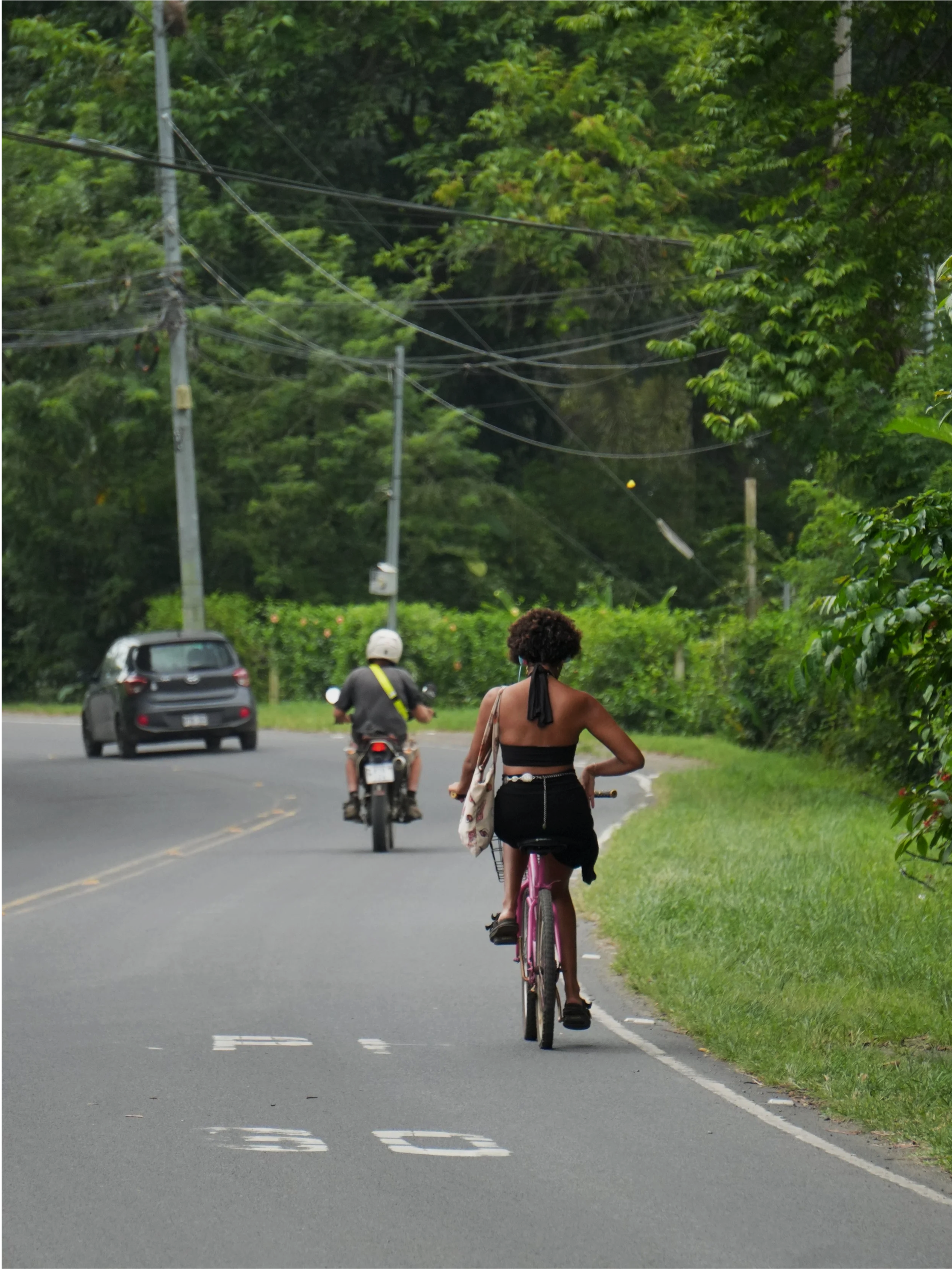 Person cycling along a quiet tropical road surrounded by dense greenery on the Caribbean coast of Costa Rica.