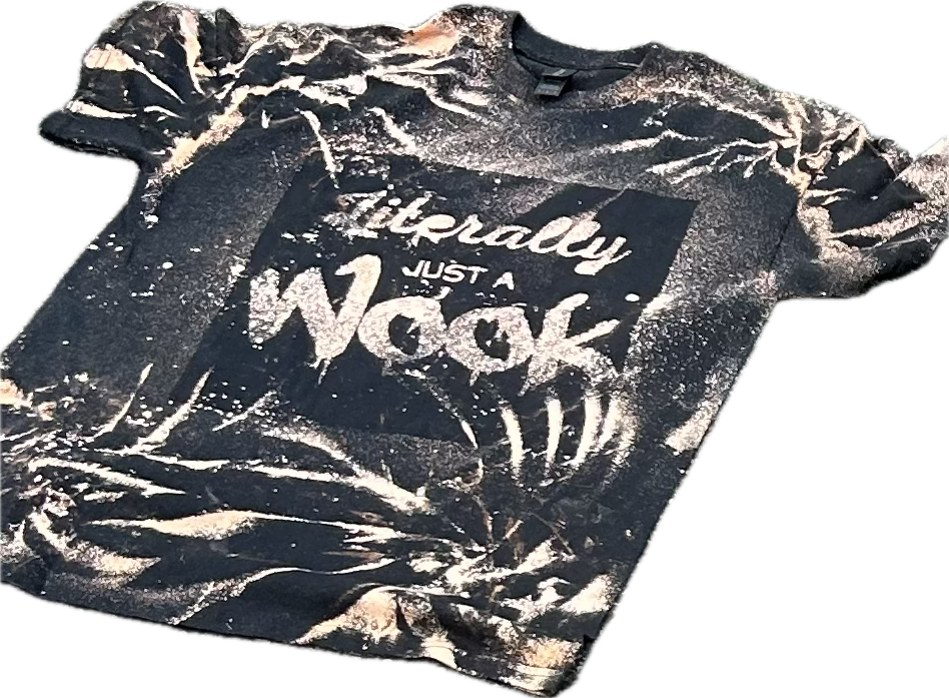 A black T-shirt with white paint splatters and the words "Literally just a Wok" printed on it. The T-shirt appears to be crumpled and laid flat.