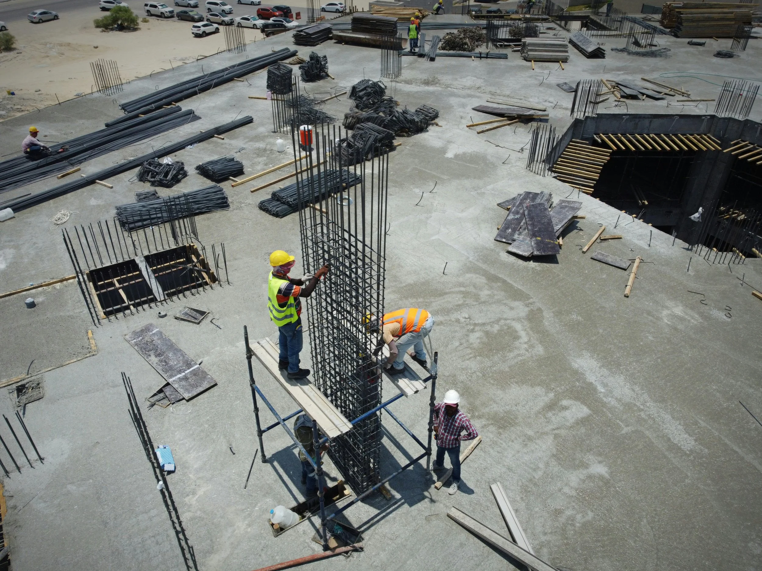 Construction workers assembling steel rebar columns on a concrete building site