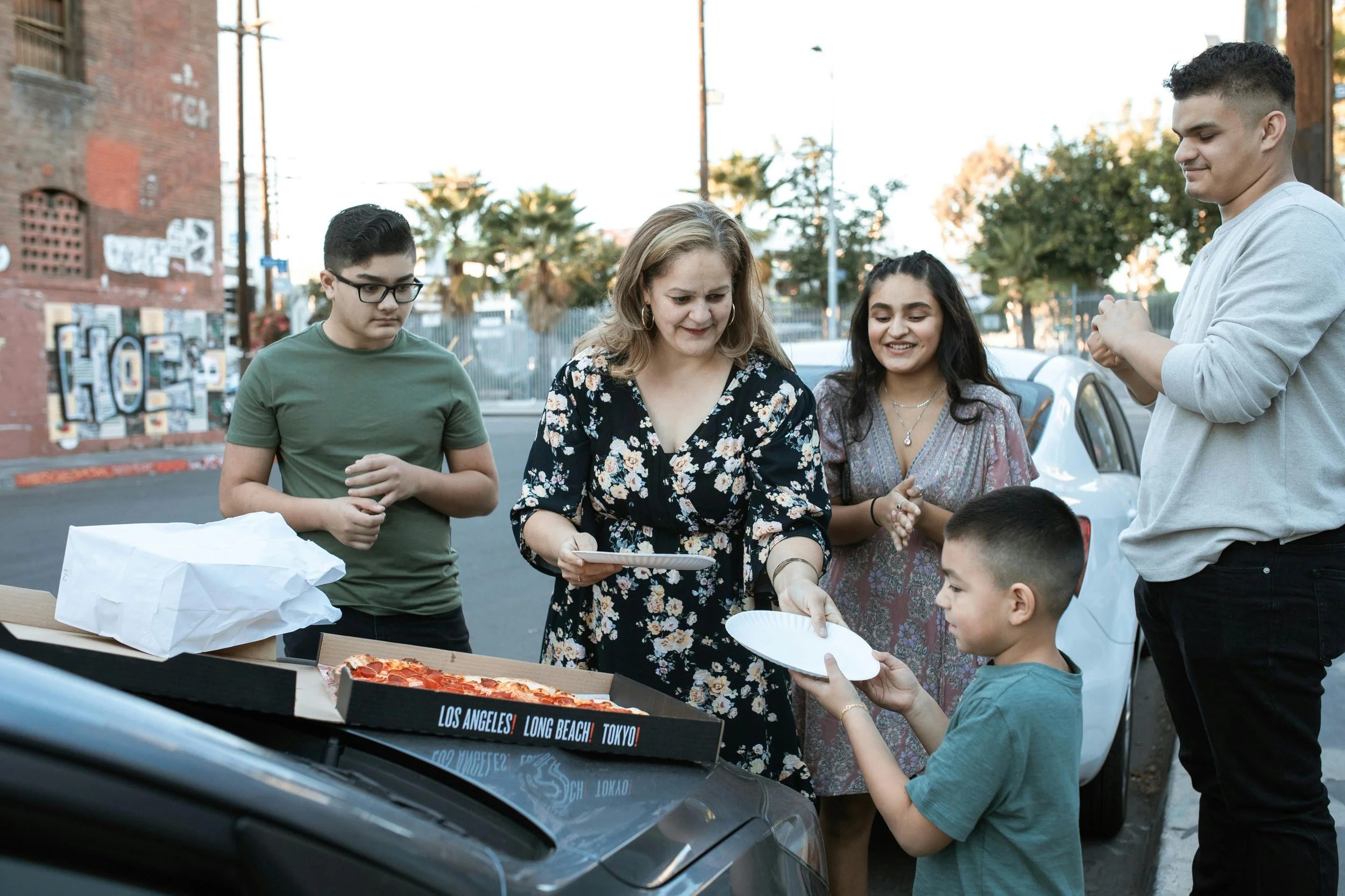 People serving pizza to a child outdoors during a community gathering