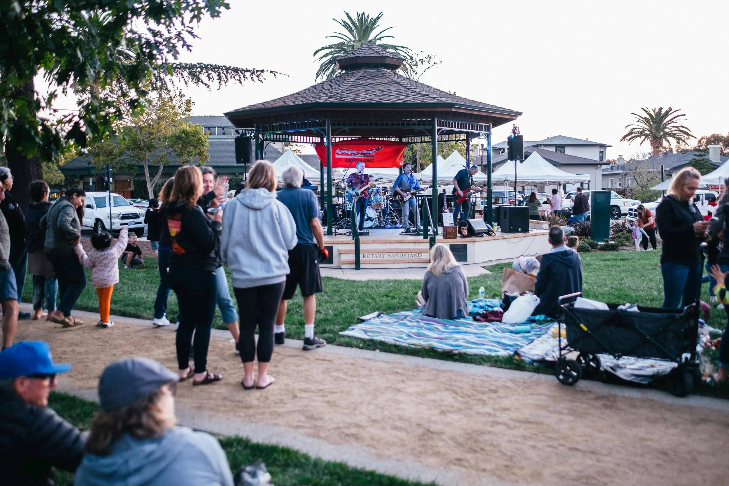 Outdoor band performing on a gazebo stage as people watch in a park
