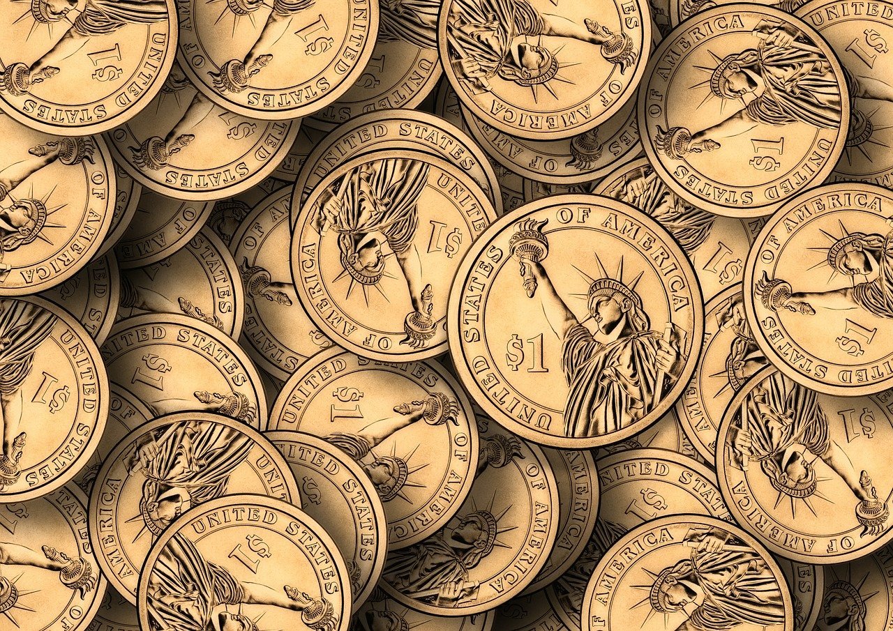 A pile of U.S. one-dollar coins featuring the Statue of Liberty on the obverse side.