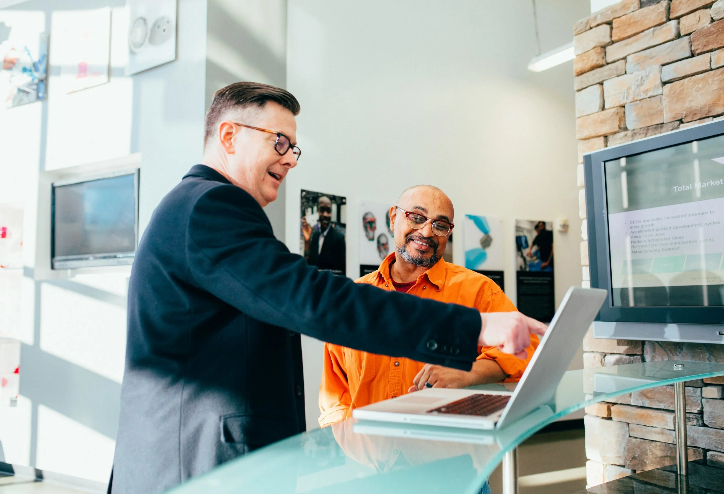 Two people standing at a counter reviewing information on a laptop