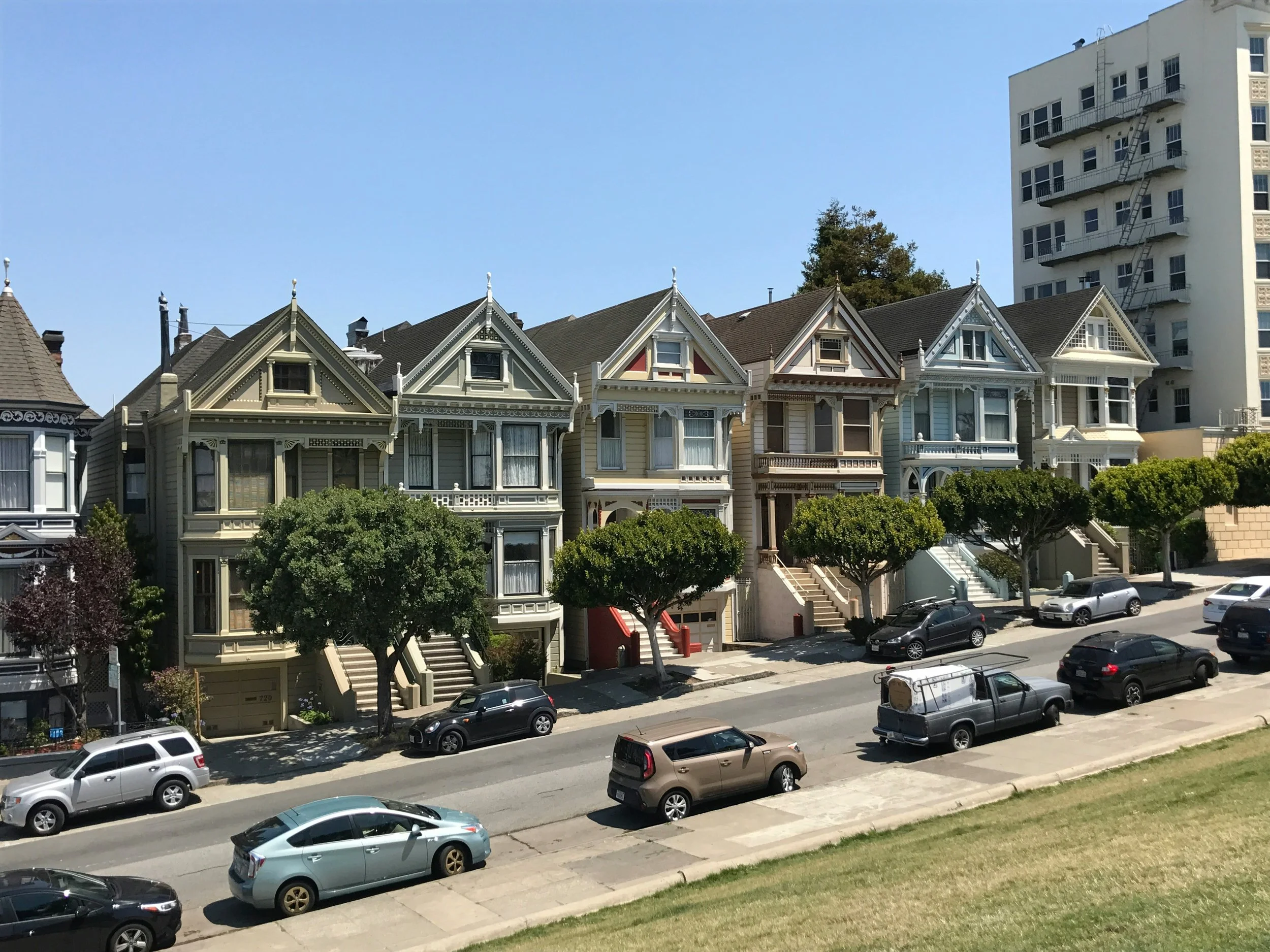 Colorful Victorian houses lined up along a sunny urban street