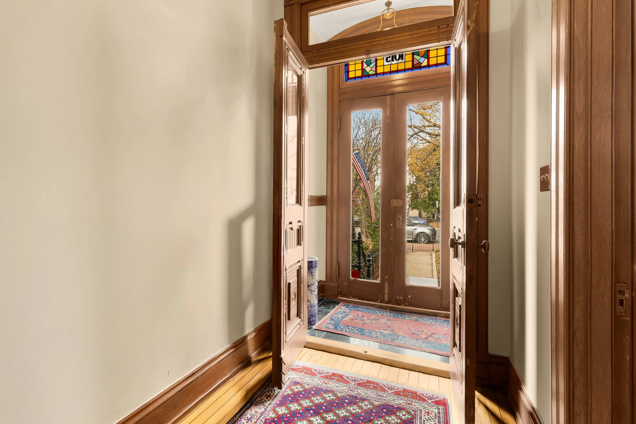 Front entryway of a house with a wooden door, stained glass window, and an American flag outside