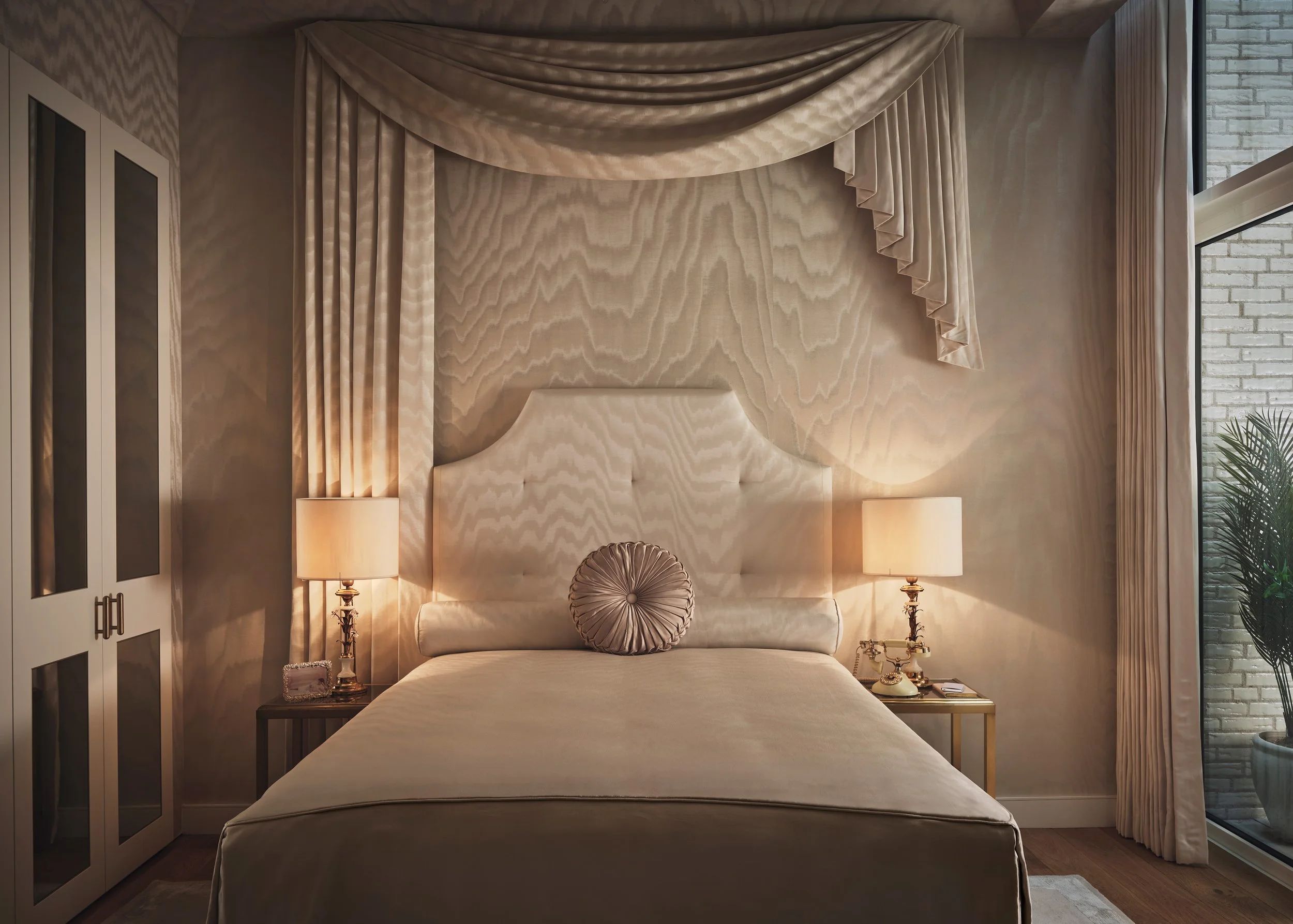 Hollywood Regency bedroom with upholstered bed, draped canopy and Dedar wallcovering by Studio L London
