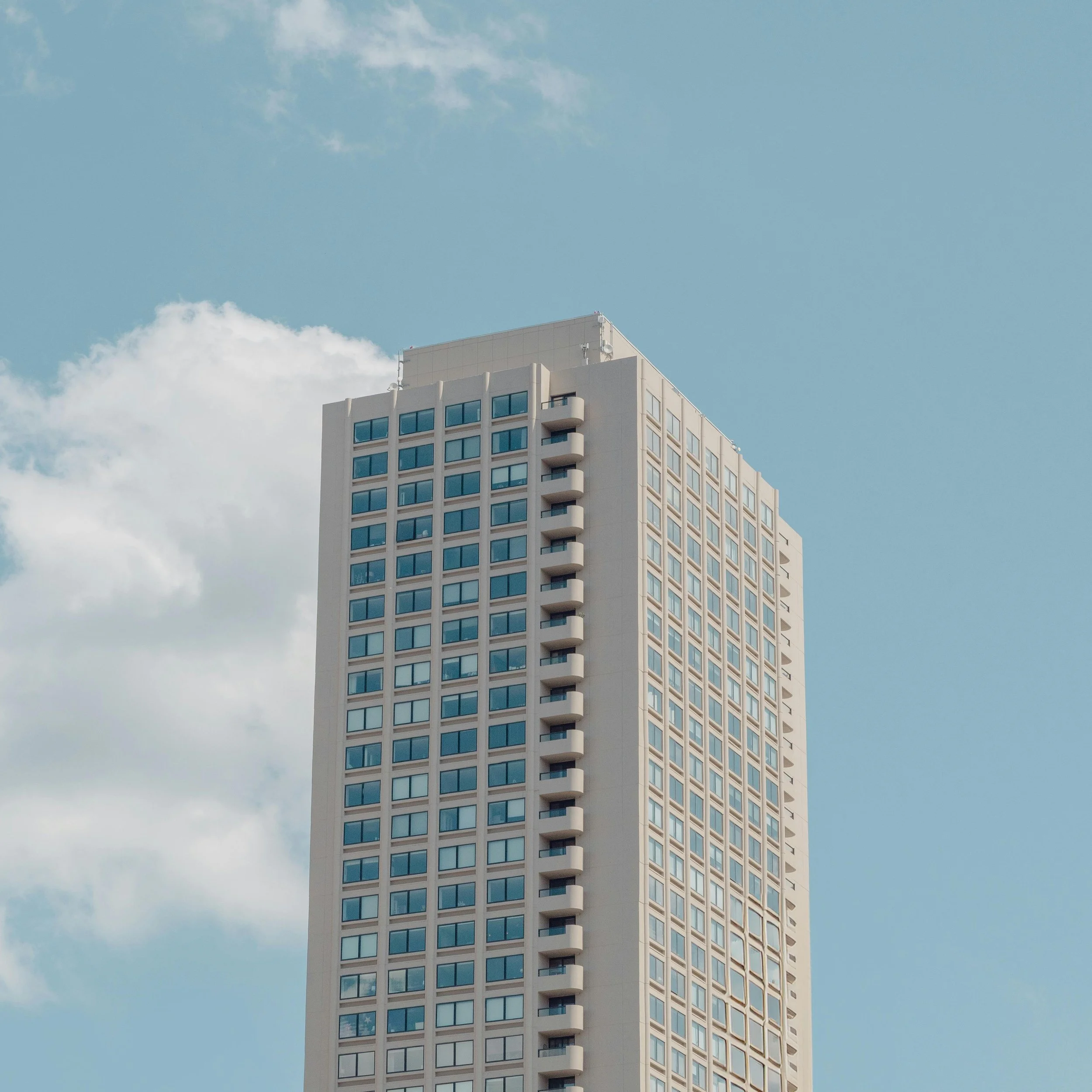 High-rise building with numerous windows under a partly cloudy sky.
