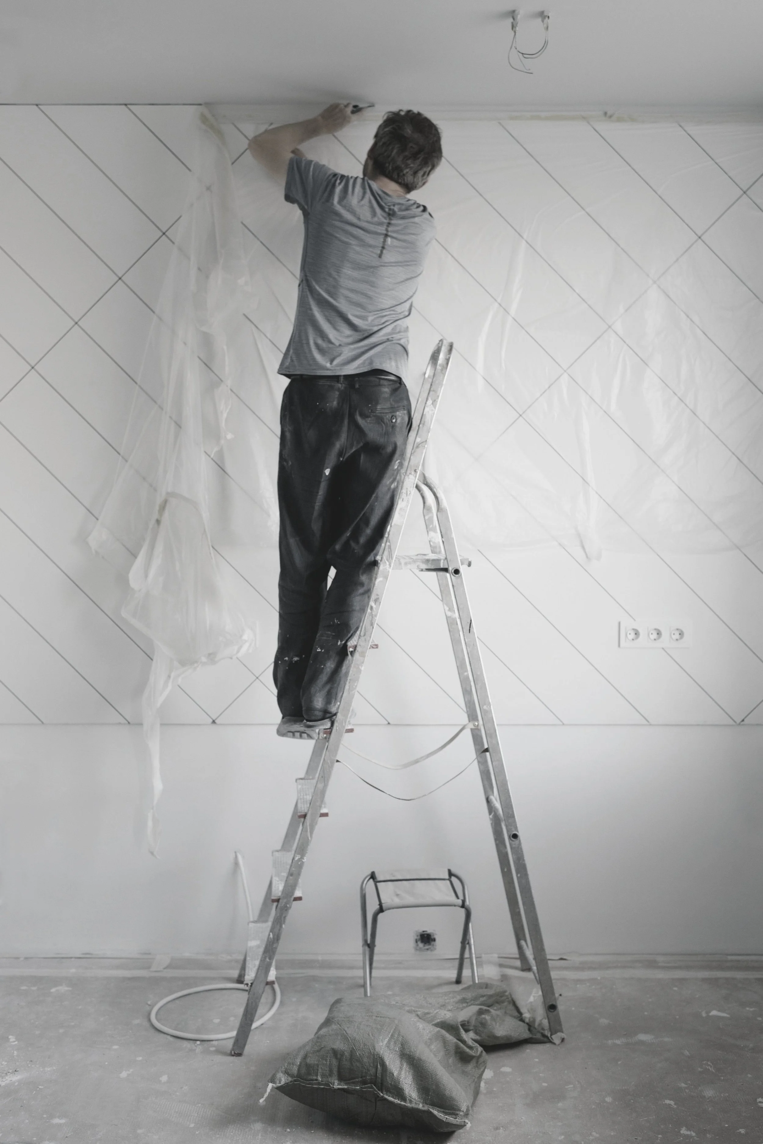 Image of a person standing on a ladder, painting a room.