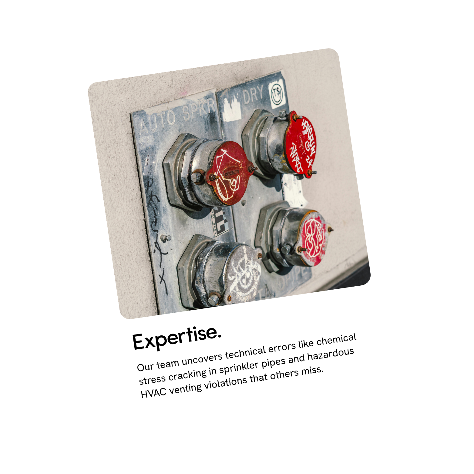 Close-up of red fire alarm switches mounted on a wall with handwritten graffiti. The switches are labeled for auto spray and dry, with warning symbols and scribbles.