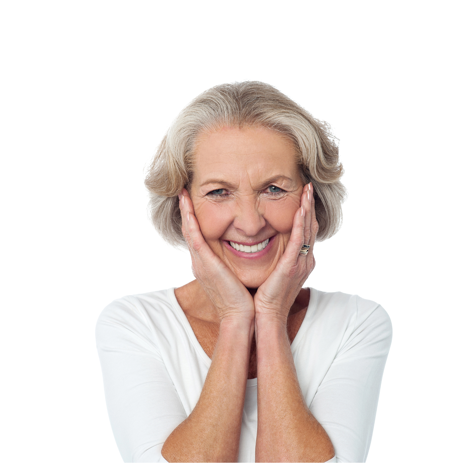A cheerful elderly woman with gray hair, smiling widely, holding her face with both hands, wearing a white shirt.
