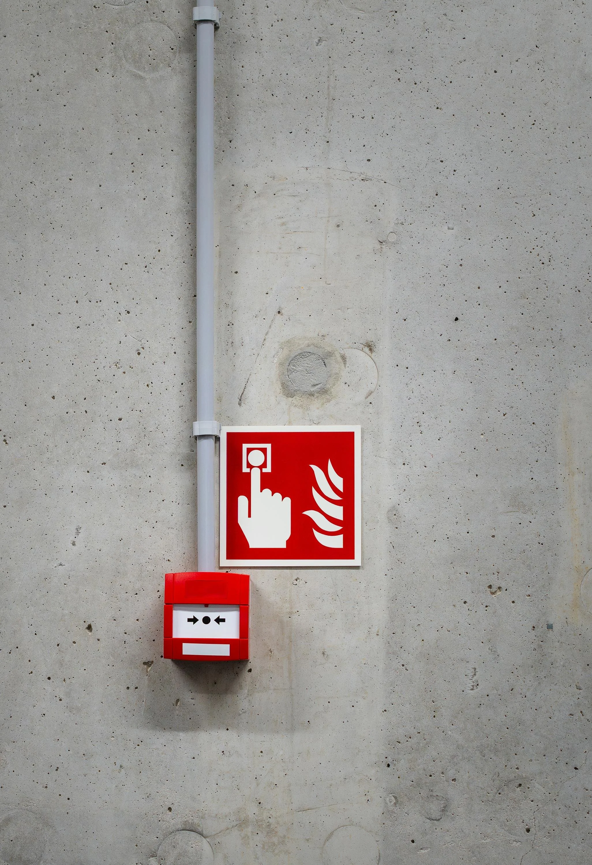 A fire alarm system with a red box and a sign indicating fire alarm activation on a plain concrete wall.