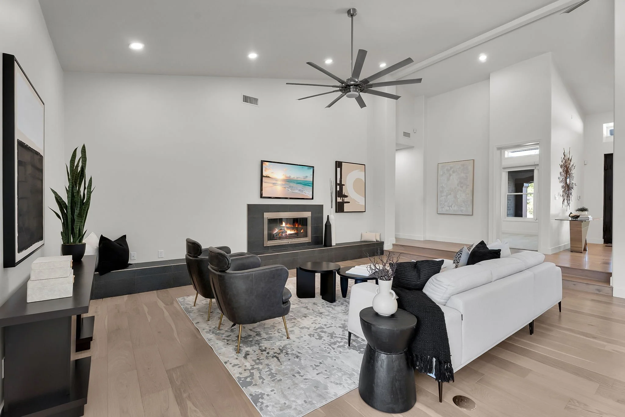Modern living room with a white sofa, black chairs, a fireplace, and art on the walls.