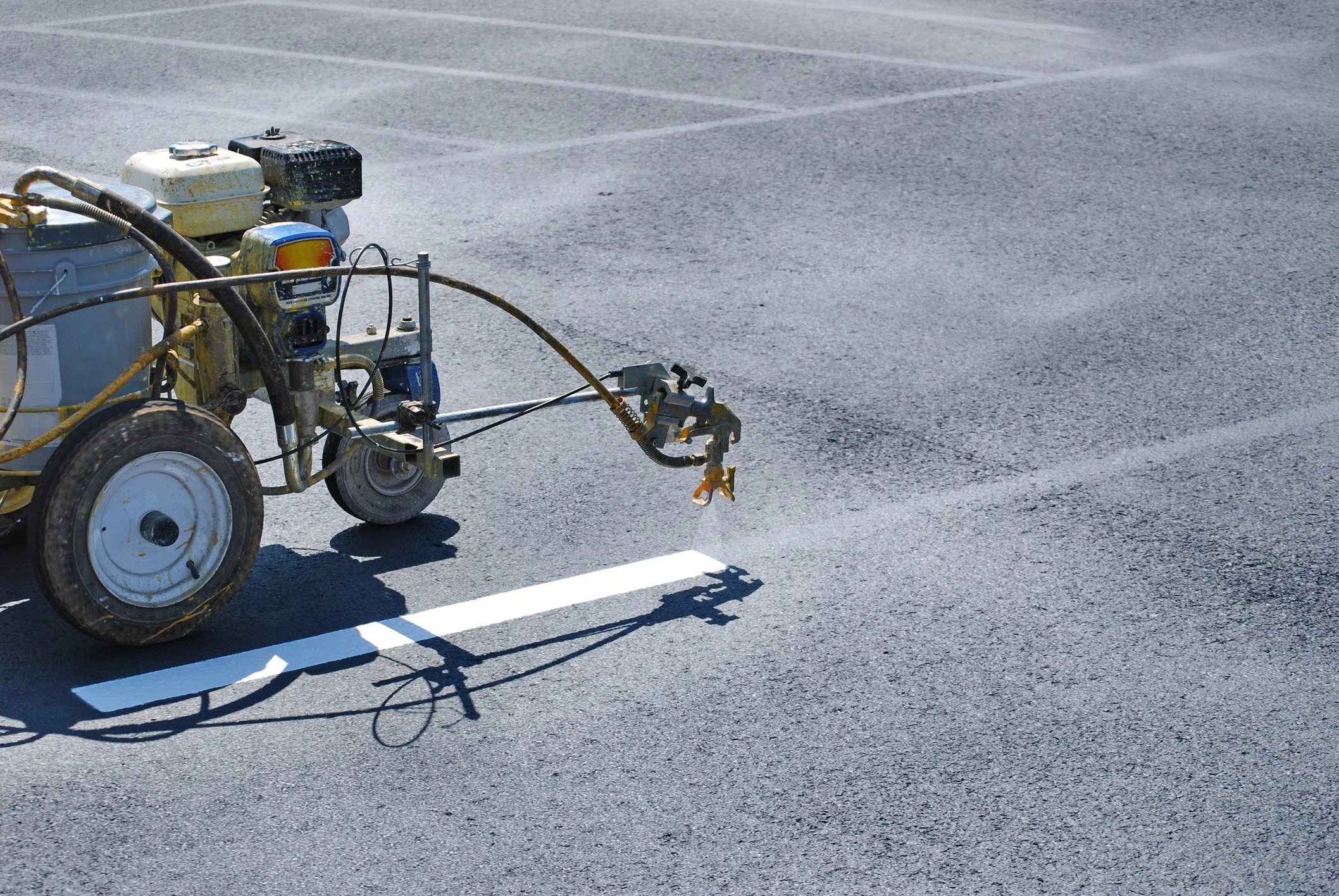 A paving machine painting white lines on an asphalt road.