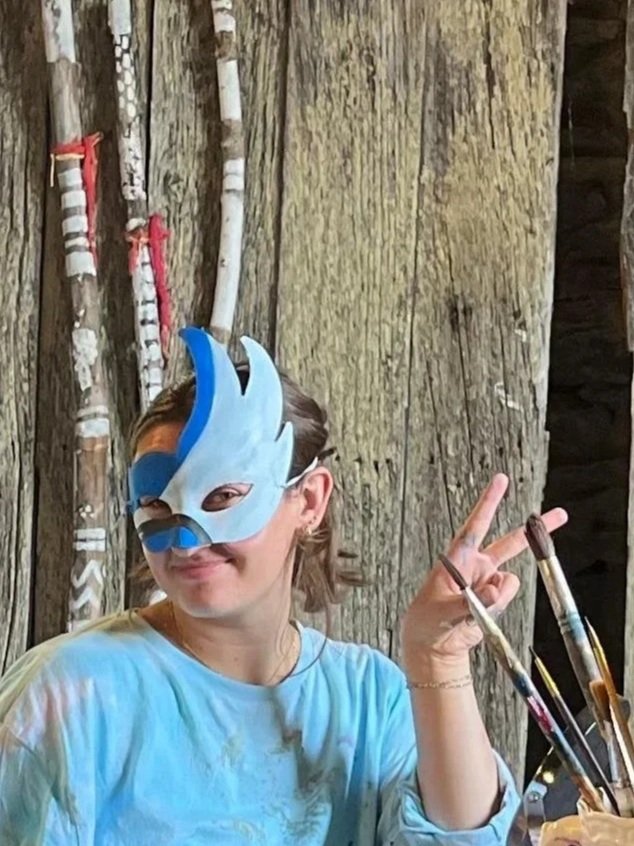 girl wearing blue mask while smiling and giving "peace" sign