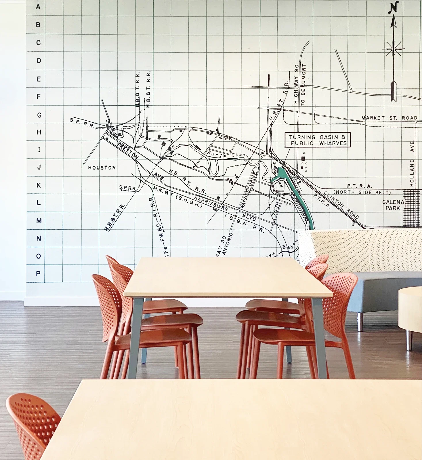 A room with tables and chairs, featuring a large wall mural of an old city map with streets and landmarks.