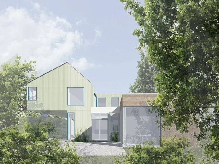 Modern house with angular design, large windows, situated among trees under a partly cloudy sky.