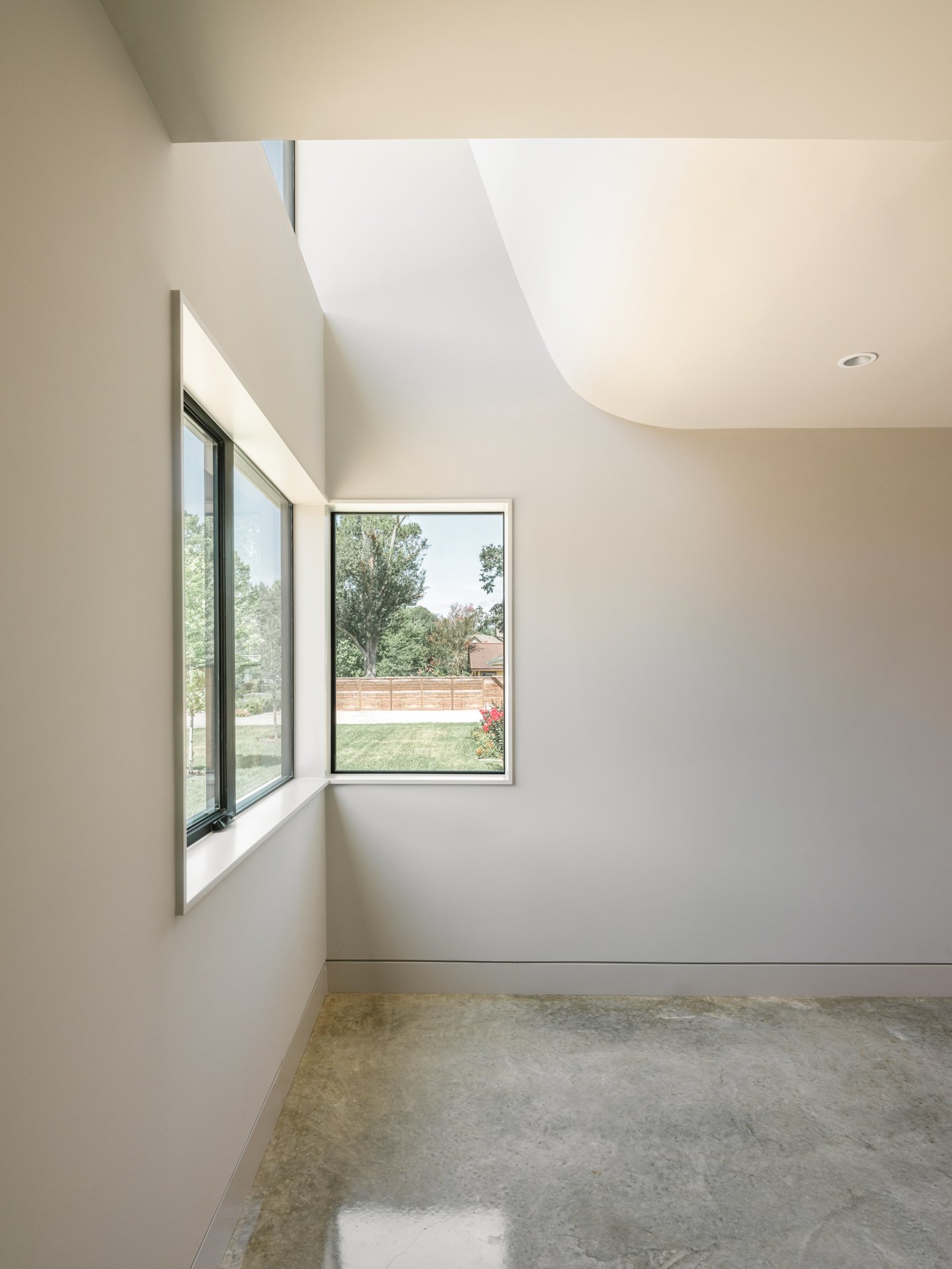 Empty room with white walls, large windows, and polished concrete floor.