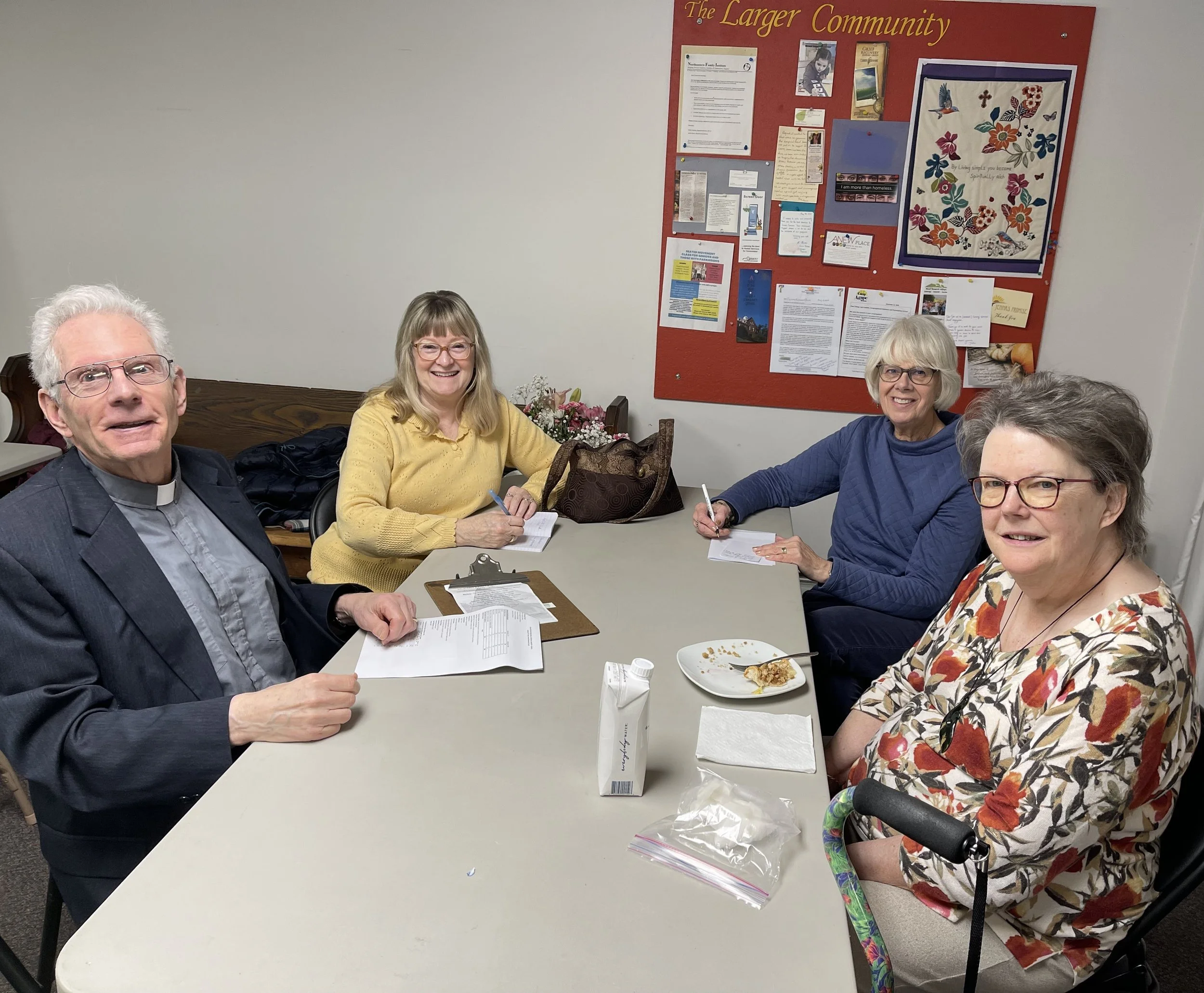 Three women and one man from the Calvary food shelf team sitting around a table discussing their plans for Christian Ministries.