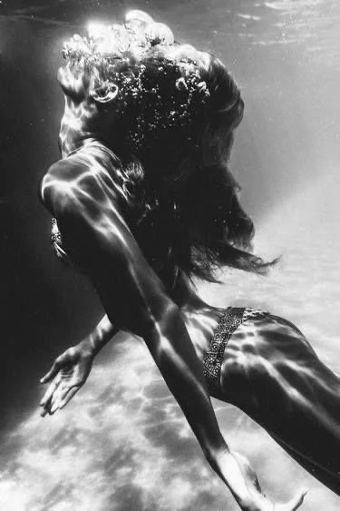 A woman underwater, wearing swimwear, with long hair flowing, in a dynamic pose. like a mermaid.