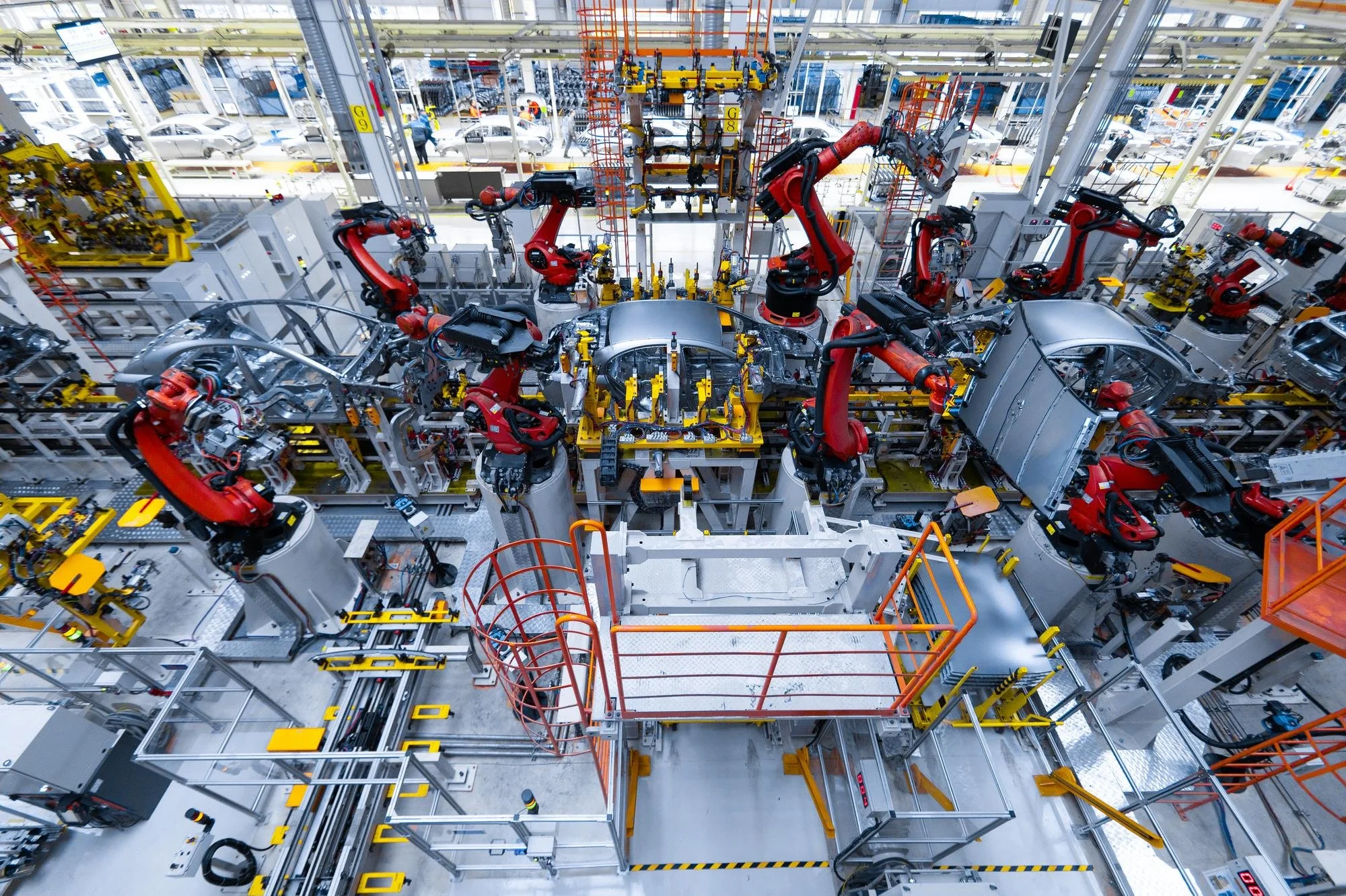 Automated factory floor with robotic arms assembling car bodies.