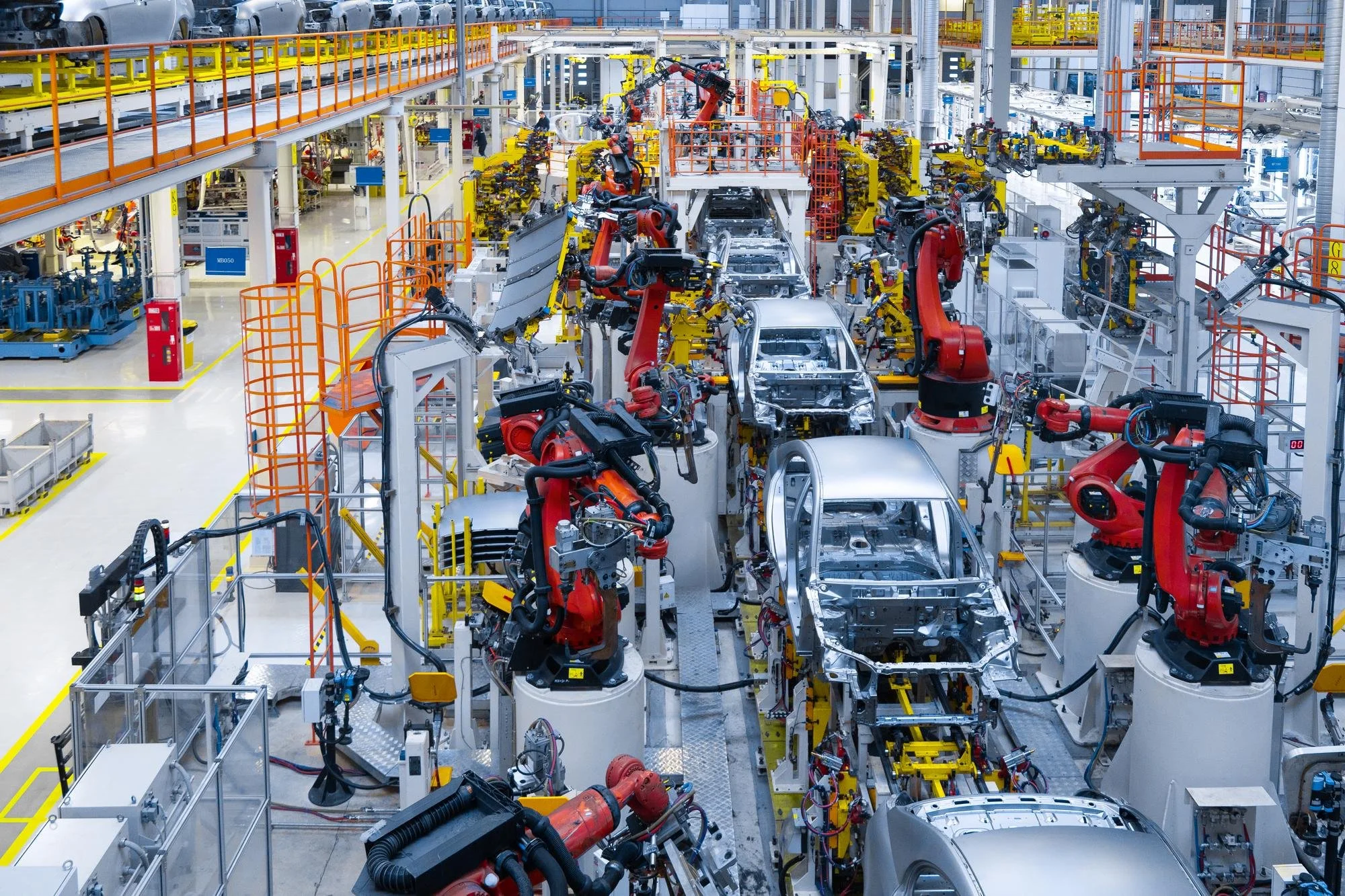 Automated industrial robots assemble car bodies on an automotive production line in a factory.