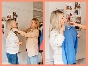 A woman is helping a girl try on a blue sweater in a room decorated with pictures on the wall.