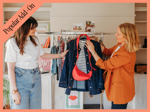 Two women shopping for clothes in a boutique, examining a denim jacket with a red purse, surrounded by racks of clothing.