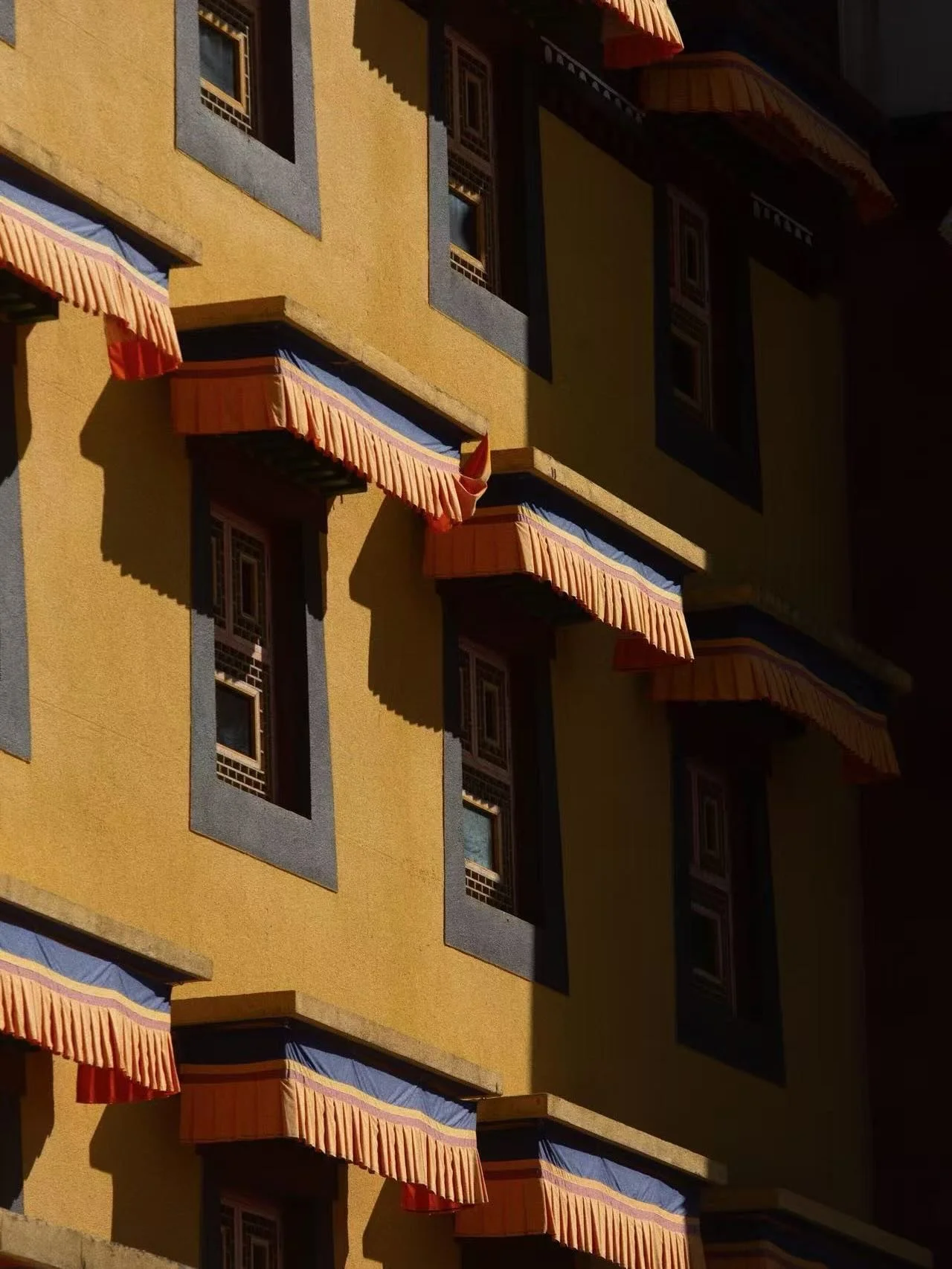 Across Tibetan regions, window ornamentations are as symbolic as they are expressively beautiful. Deep reds, ochres, indigo blues, and mineral greens are layered in bands and frames, often paired with geometric borders or hand-painted motifs that sig
