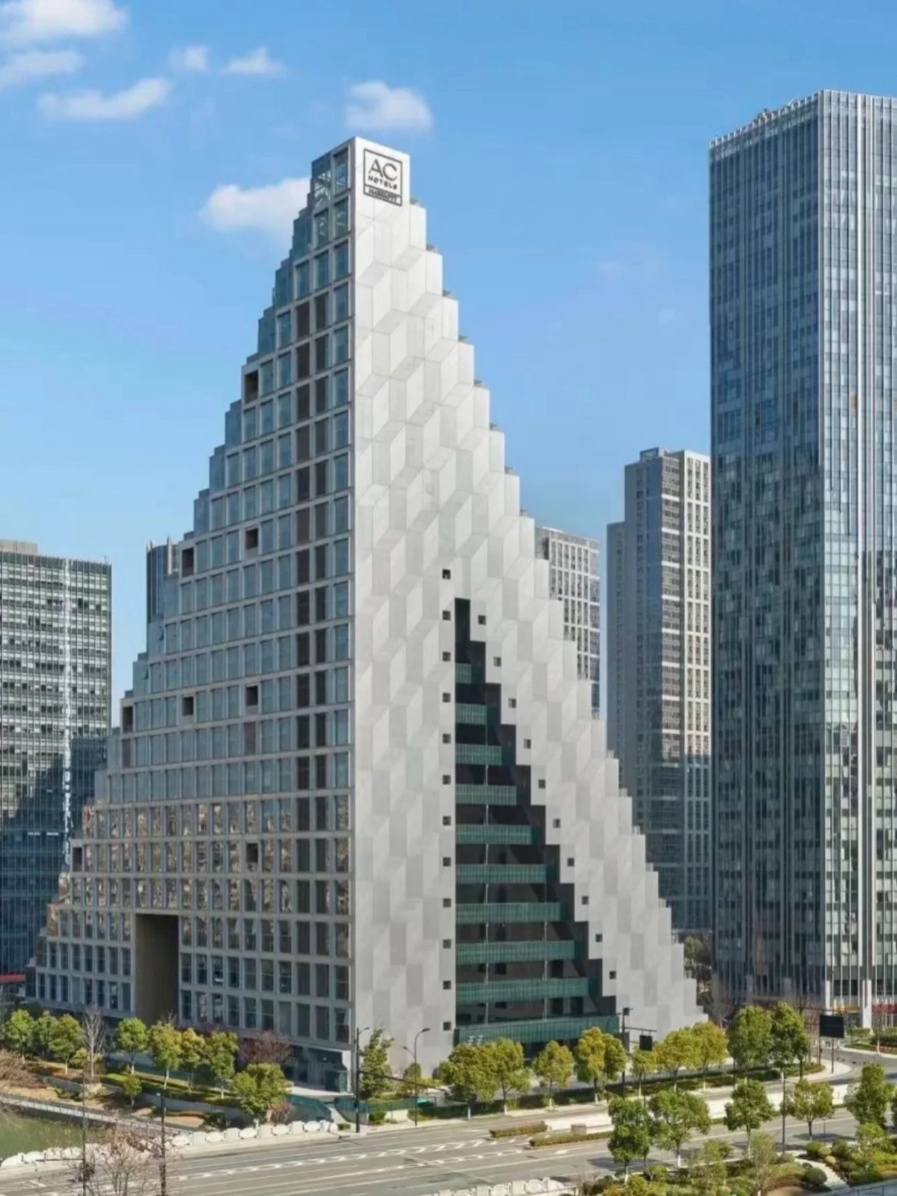 Designed by OMA, the Hangzhou Prism AC
Hotel eschews the conventional hotel tower for a more sculptural approach, using geometry, cascading terraces, and light to shape the guest experience. Embedded within the mixed-use Prism development in Hangzhou