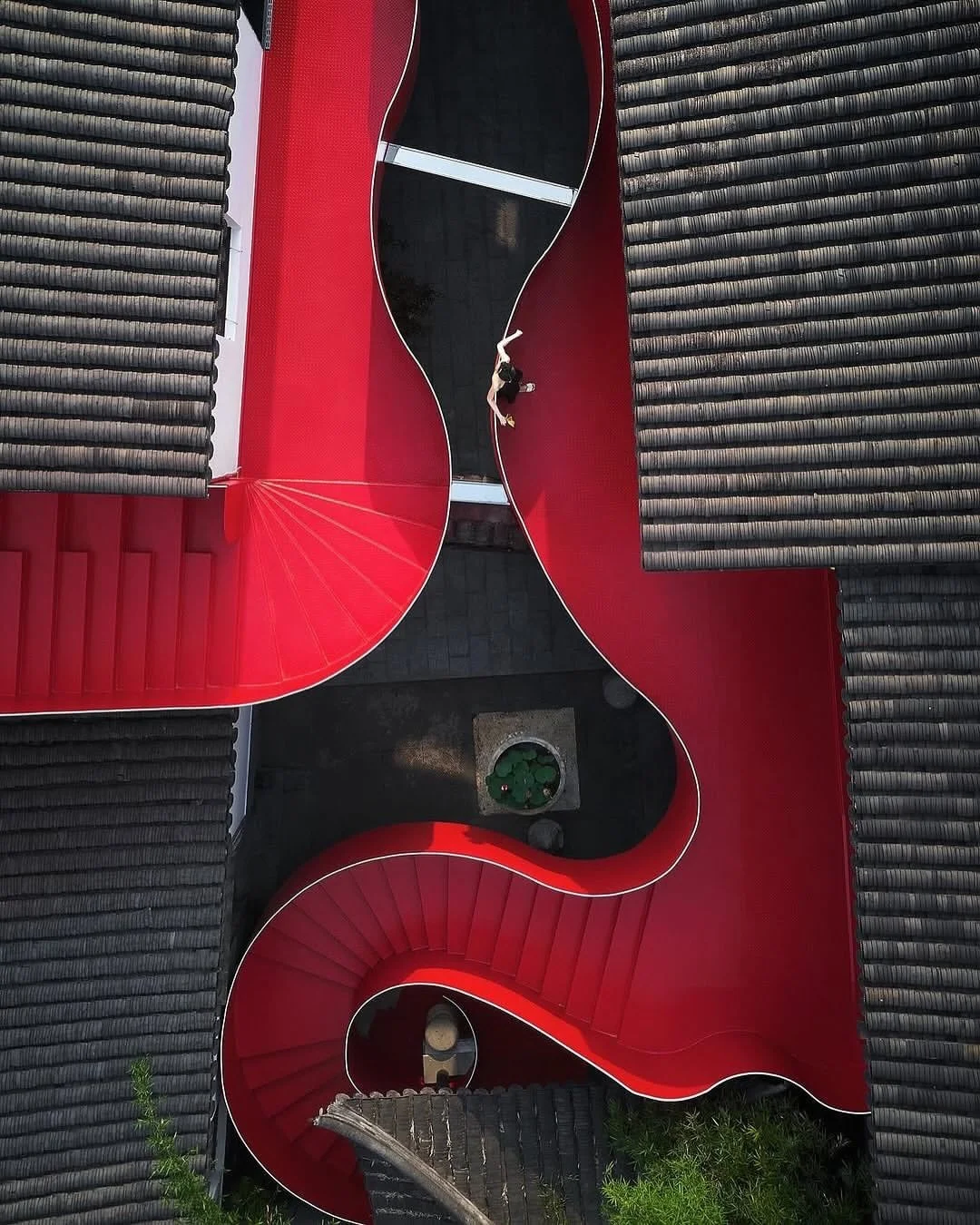 Along the Qinhuai River in Nanjing, a sinuous red steel staircase stitches together a cluster of historic courtyard buildings at Big Red Crayfish. Dayi Design renovated the 2,000sqm site as a dining and commercial space while retaining its existing a