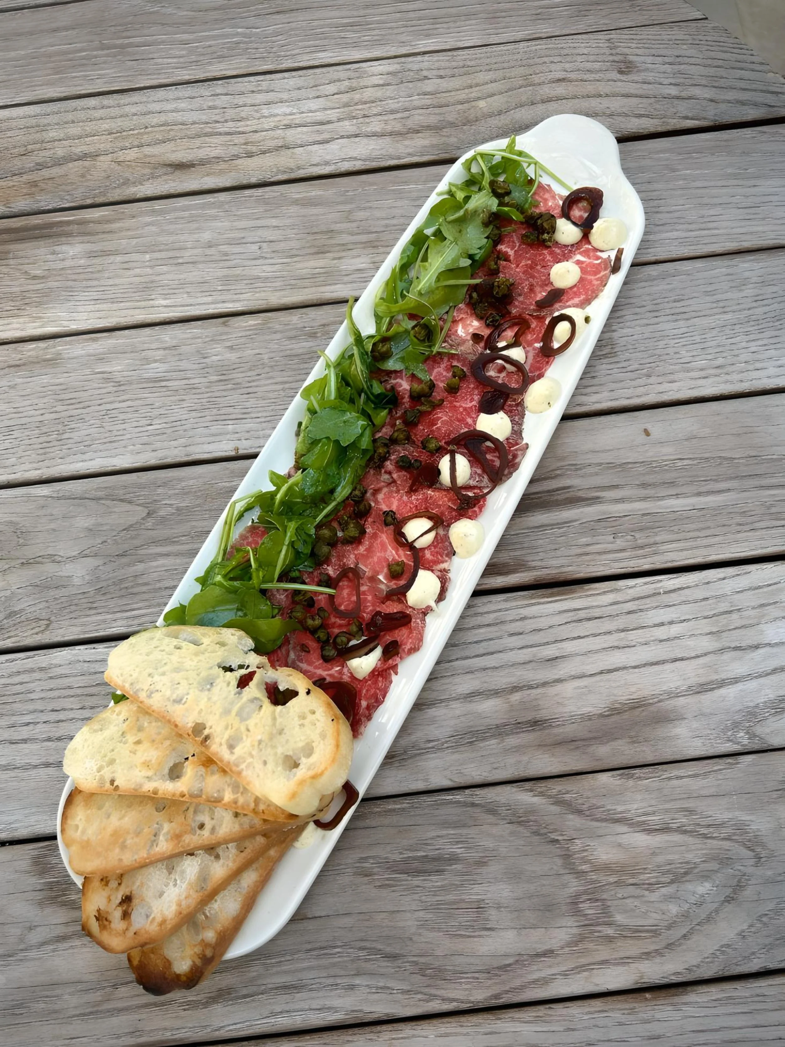 Dry Aged Wagyu Carpaccio, Balsamic Pickled Shallots, Smoked Beef Fat Aioli, Arugula, Topped with Fried Capers and Served with Crustinis
