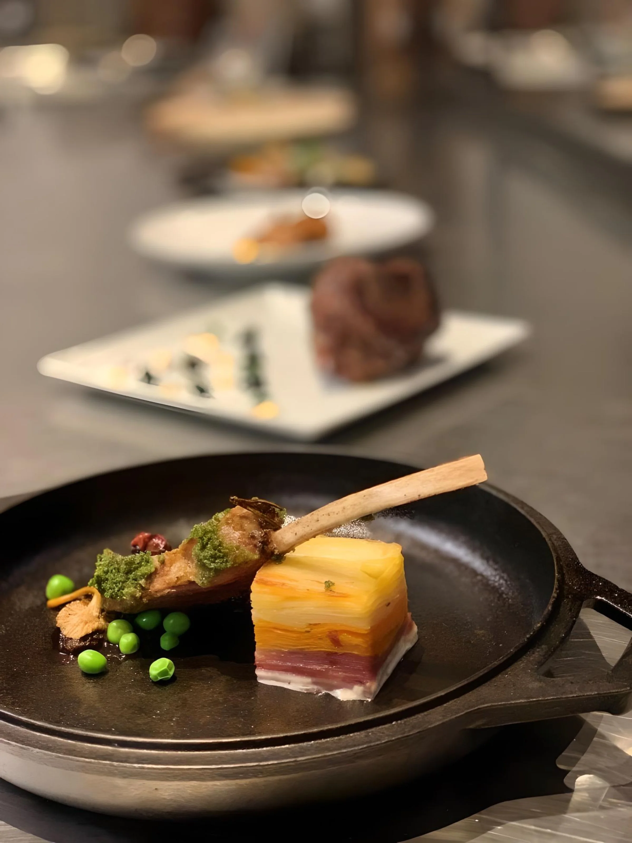 Dry Aged Lamb, Tri Color Au Gratin, Peas, and Wild Mushrooms, Topped with an Herb Gremolata 