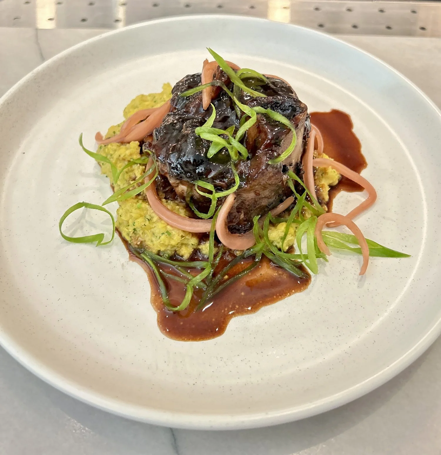 Pork Osso Bucco, Corn Hash, Charred Compressed Nectarines, Pickled Onions, Veal Jus, Green Onion Curls  