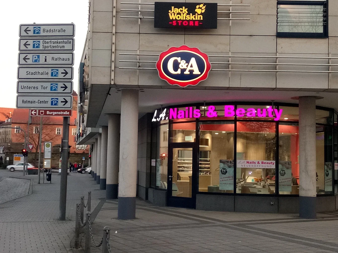 Straßenansicht eines Geschäftsgebäudes mit den Schildern 'Jack Wolfskin Store', 'C&A' und 'L.A. Nails & Beauty'.