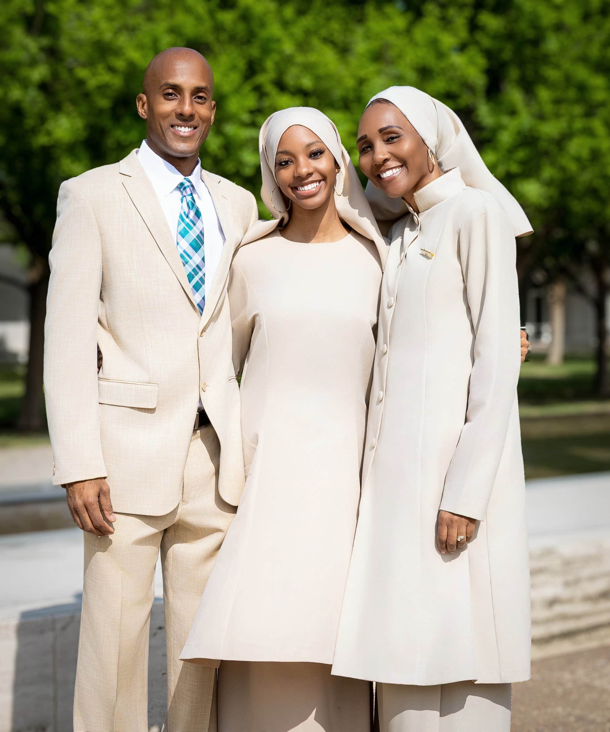 Three people smiling outdoors in formal attire, with a man on the left and two women on the right, against a background of trees. Family Photographer