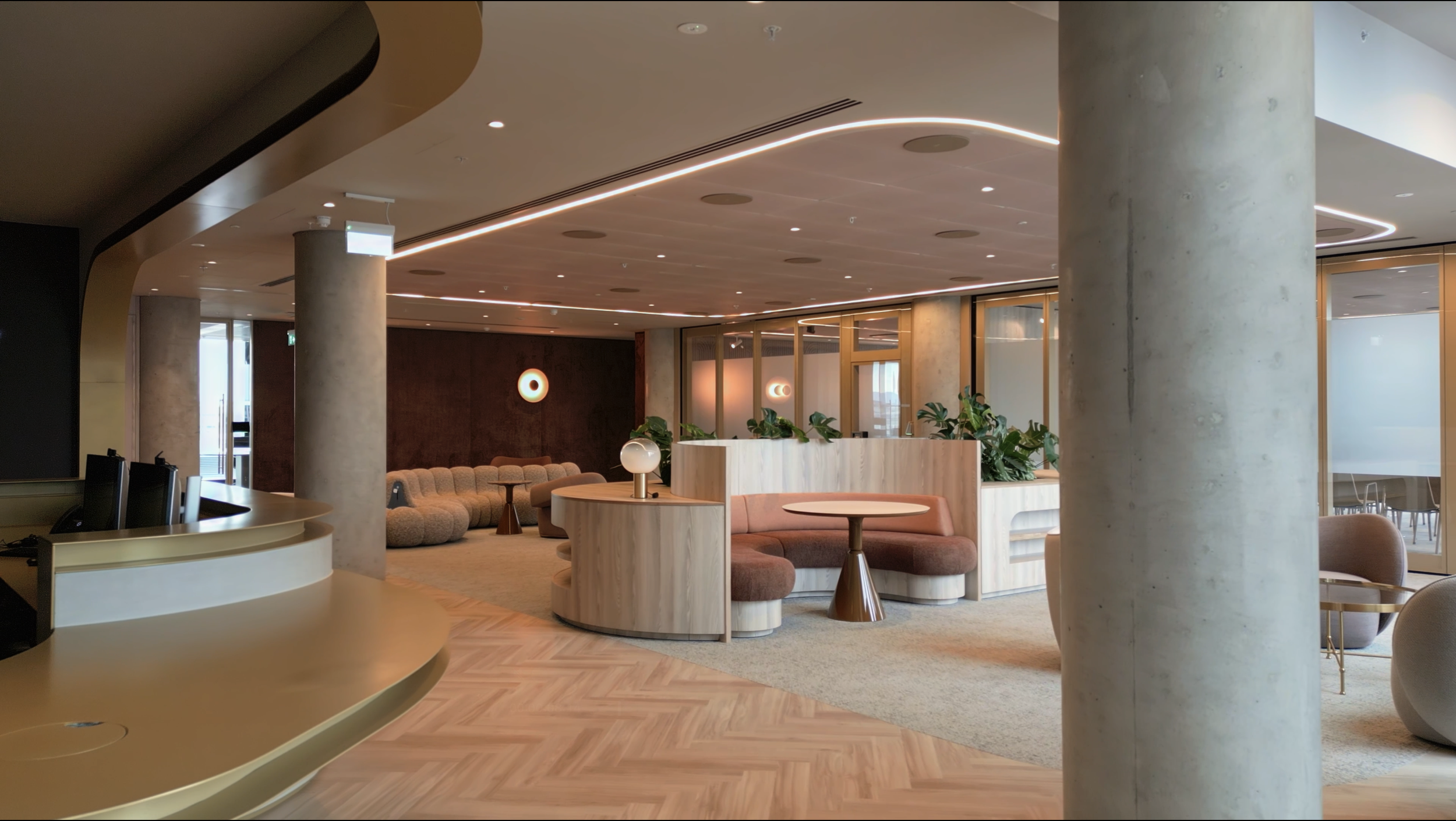 Modern, stylish lounge with sofa seating, potted plants, and soft lighting in a contemporary interior space.