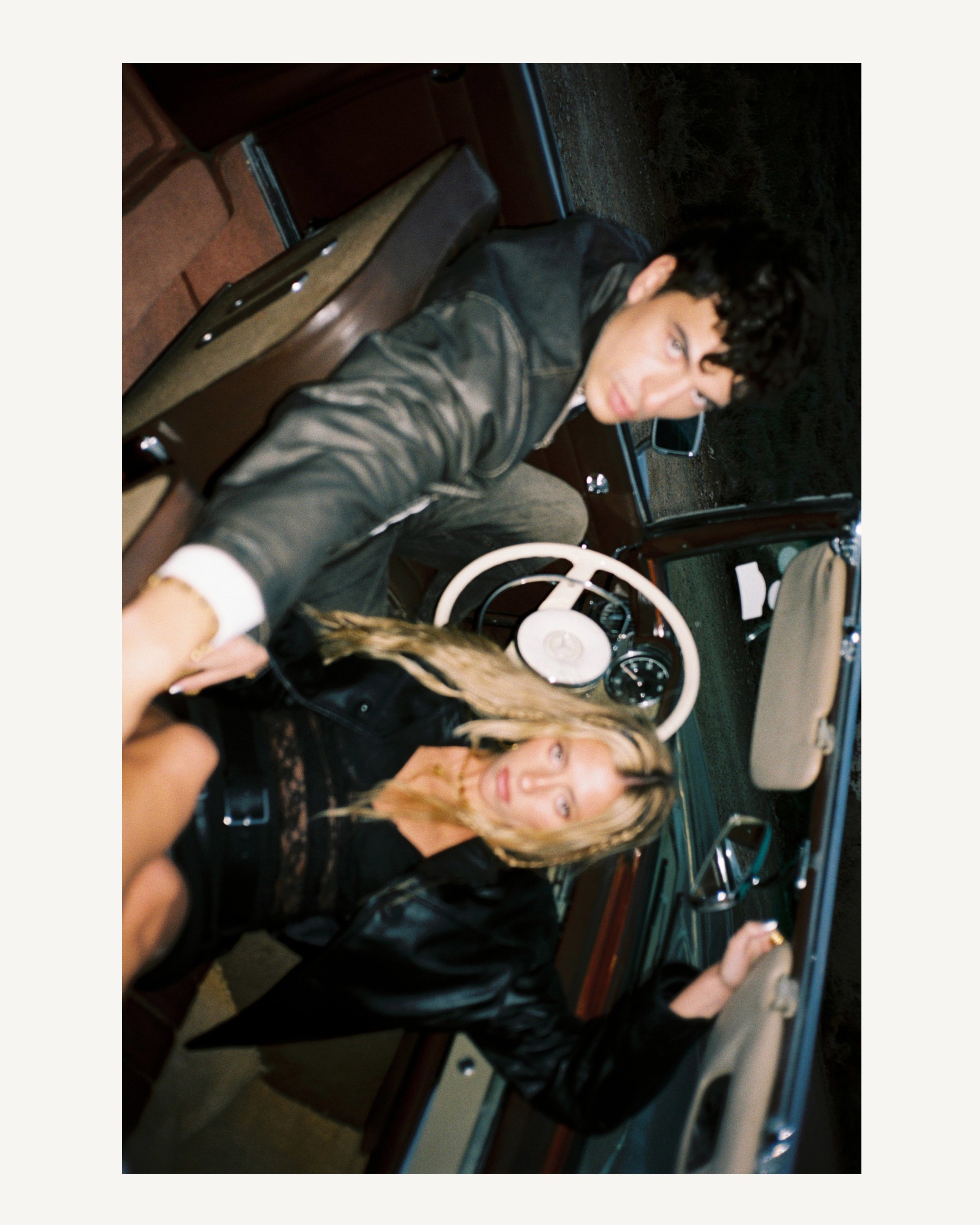 Jóvenes tomando una selfie desde un coche clásico en la noche.