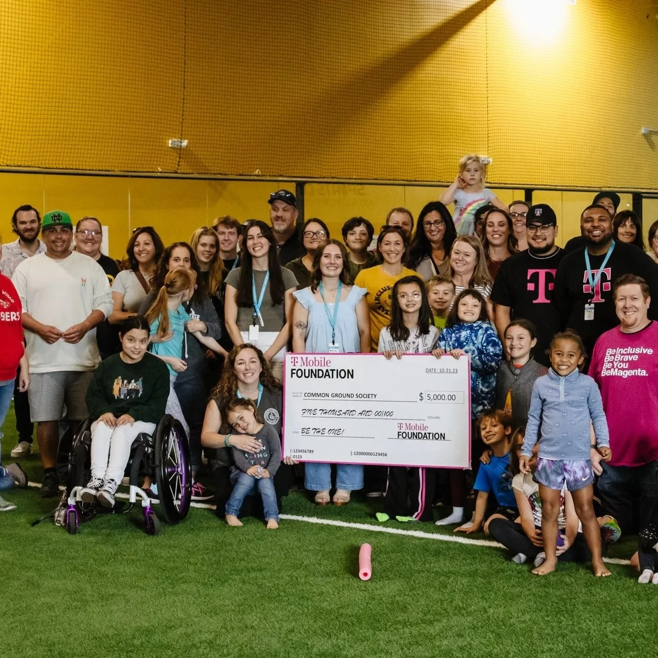 A family of four sitting outside on a blanket during autumn, with a yellow and orange tree in the background. The father and mother are smiling with two children, a boy and a girl, in front of them.