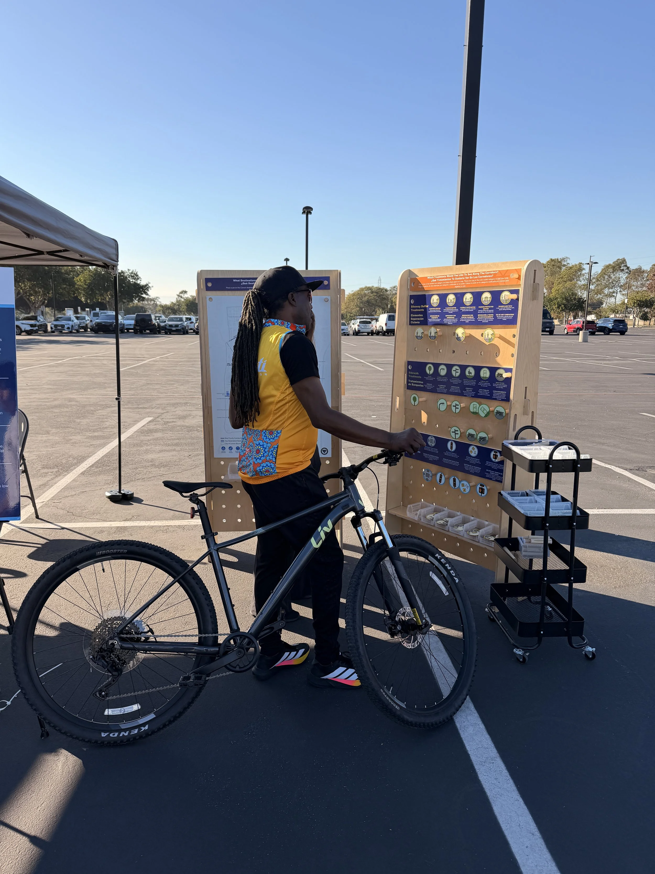 Man holding a bike while looking at outreach board