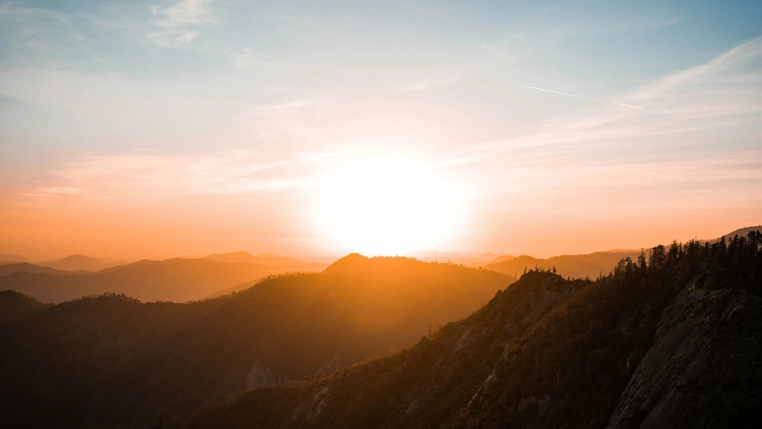 Sunset over mountain ridges with pink and blue sky.