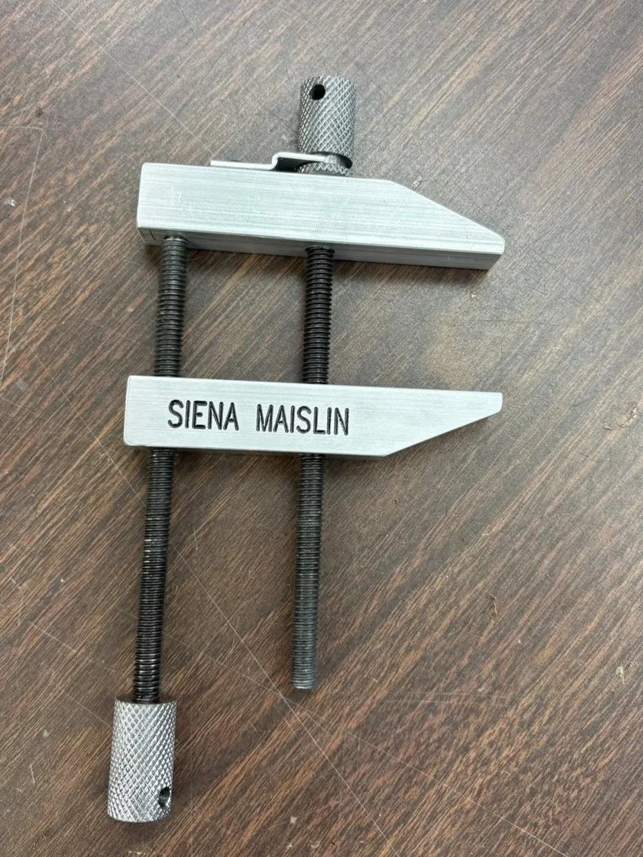 A personalized bike lock holder with the name 'Siena Maislin' engraved on it, made of metal with adjustable screws.