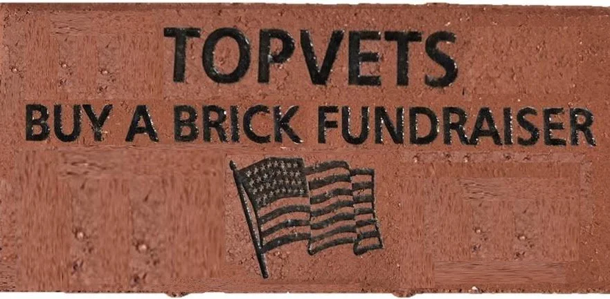 A sign with the text 'TOP PETS BUY A BRICK FUNDRAISER' and an illustration of an American flag, promoting a fundraiser for pets.