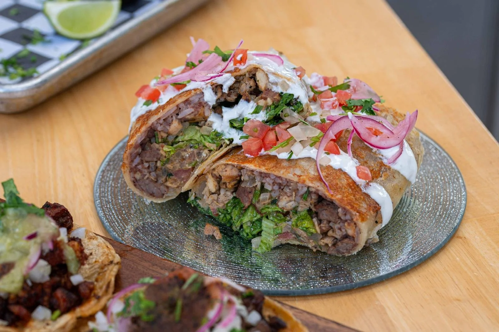 Taco de carne molida, ensalada, crema y cebolla en plato de plata.