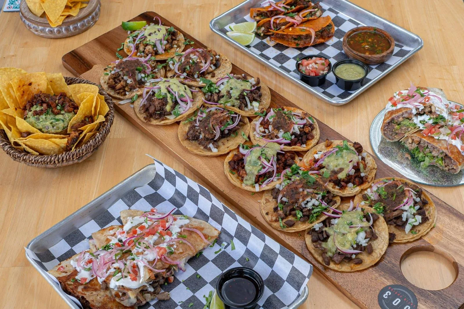 Variedad de tacos con diferentes ingredientes y salsas, acompañados de guacamole con totopos.