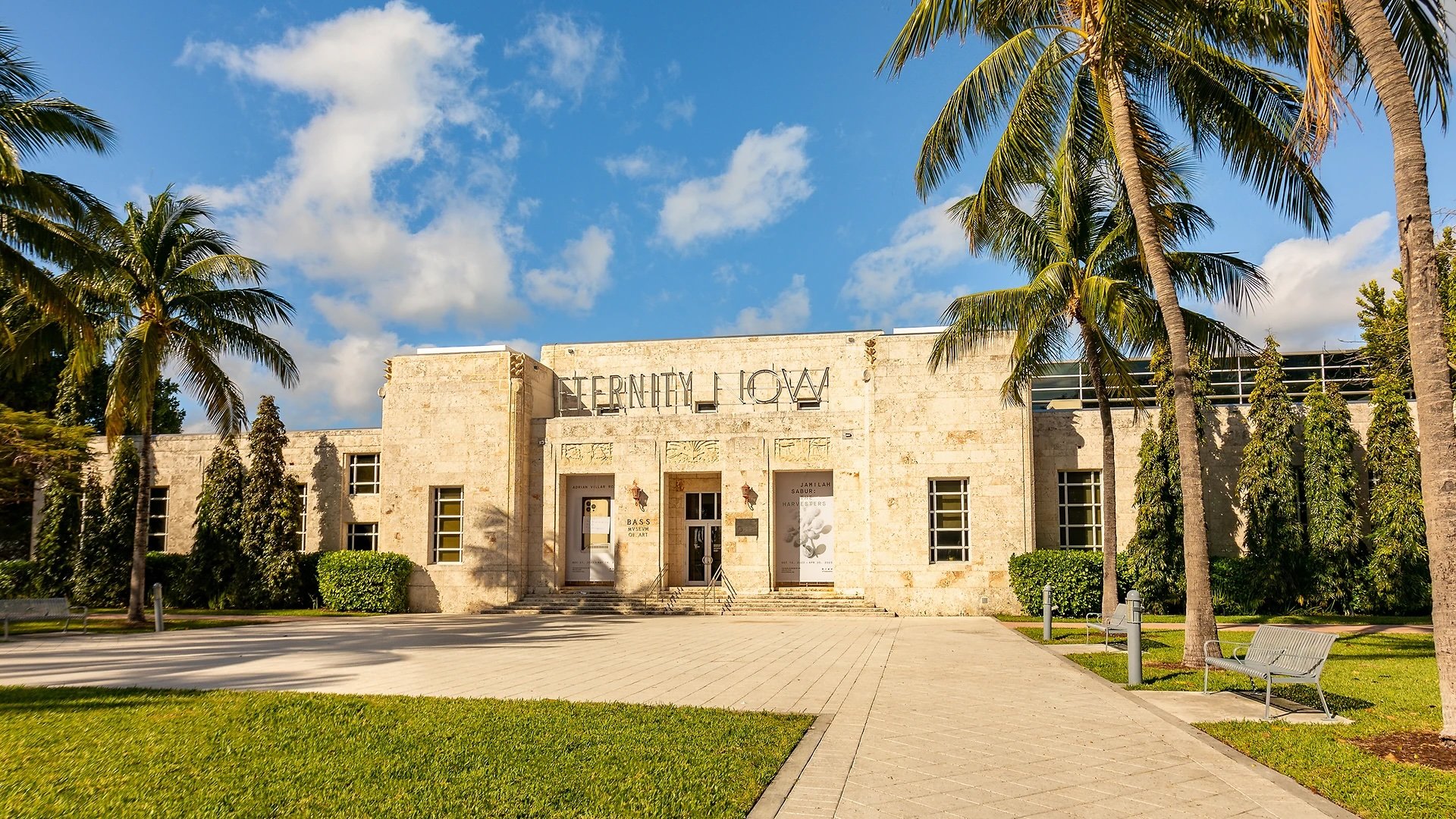 Facade of the National Museum of the American Indian in Miami, Florida, with palm trees and a sunny sky.