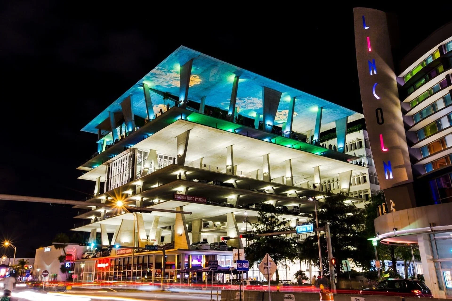 Nighttime view of The Linq hotel and casino in Las Vegas with illuminated signs, a parking garage, and a modern architectural structure with multiple levels and colorful lighting.