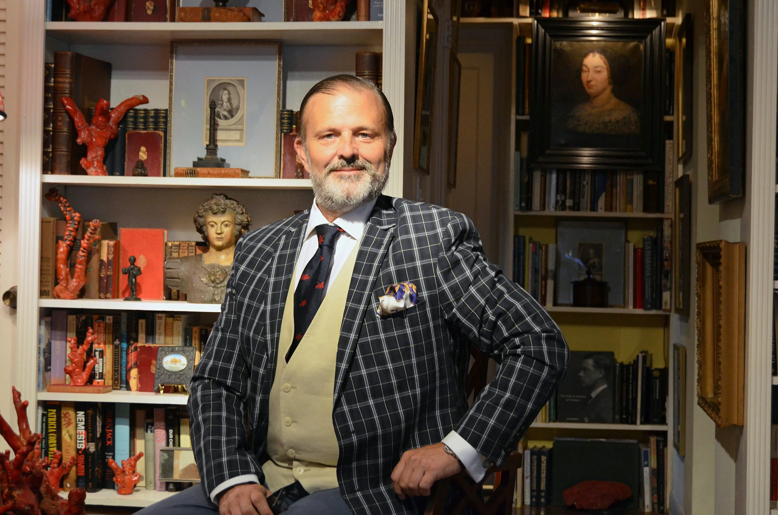 Le Basque co-founder, Alejandro Muguerza,  in a plaid suit standing in a book-lined room