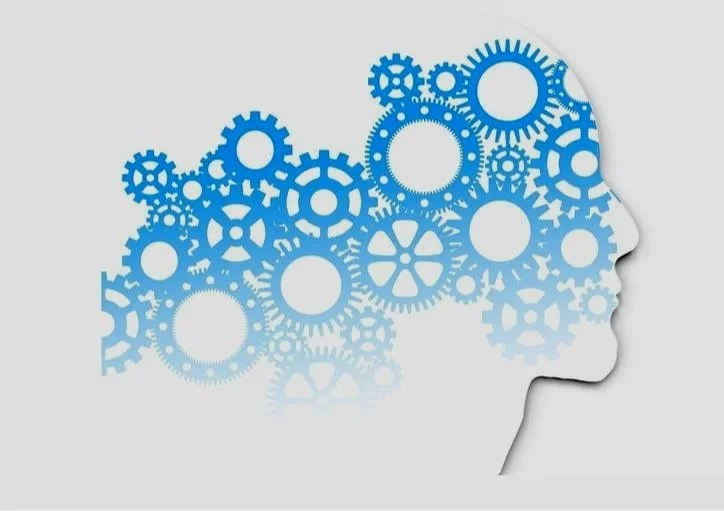 Silhouette eines menschlichen Gesichts, das mit blauen Zahnrädern gefüllt ist, die Gehirn und Gedanken symbolisieren.