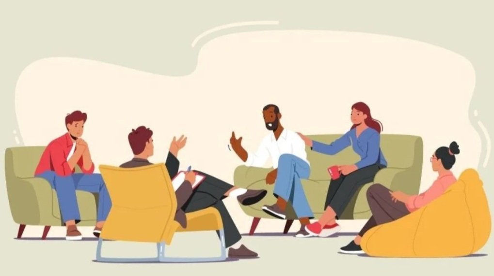 Menschen in einer Therapiesitzung, die entspannt in einem Kreis sitzen, darunter eine männliche Therapeut mit Notizblock.