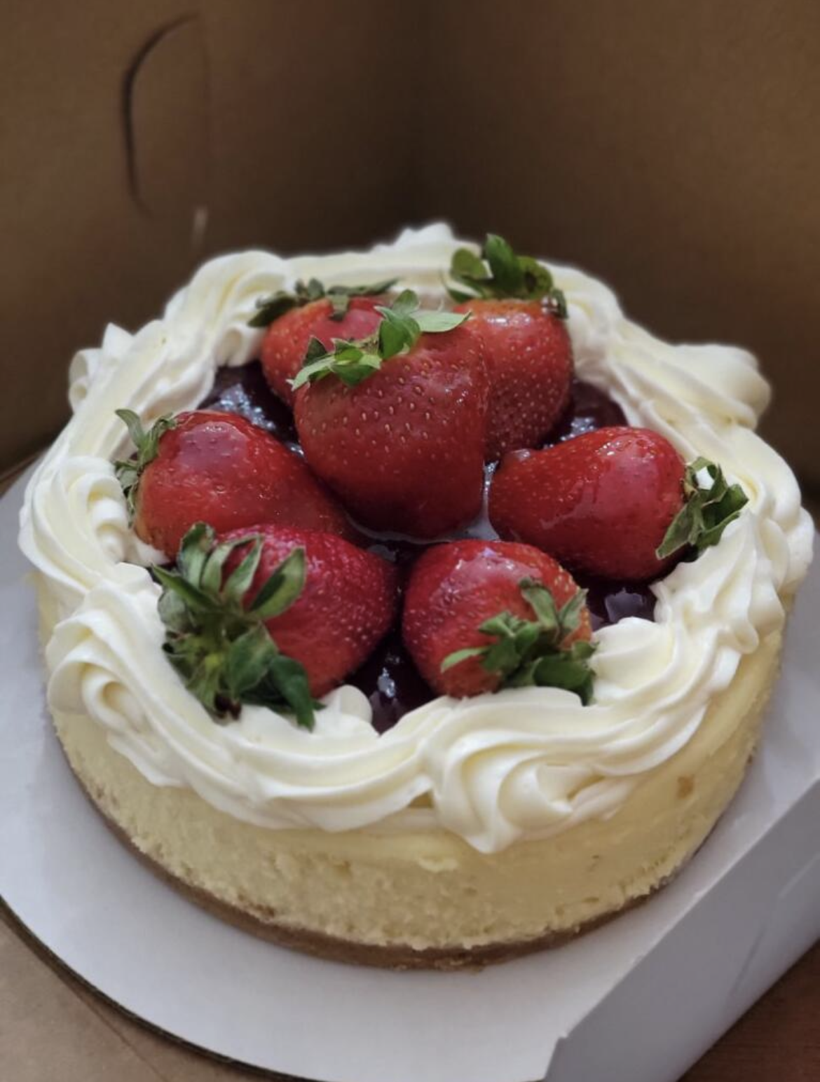 A cheesecake topped with strawberries and whipped cream.